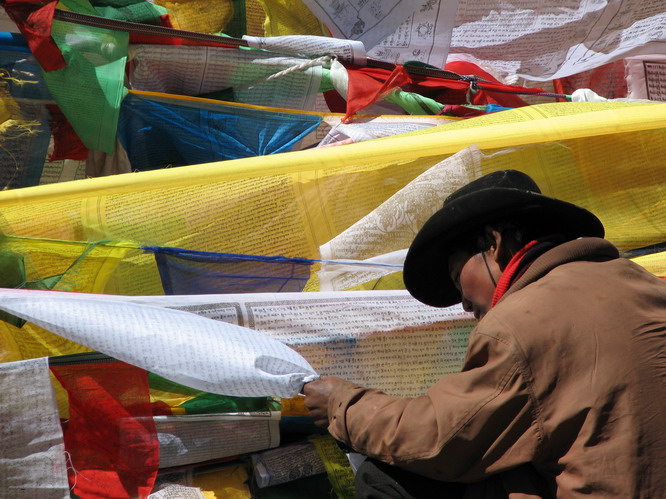 Tibetan man putting up prayer flags on Dromala Pass, Mt. Kailash.